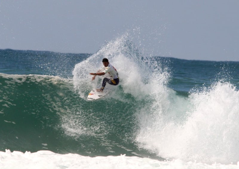 Surfer walking on the beach toward the ocean, Quiksilver rash guard